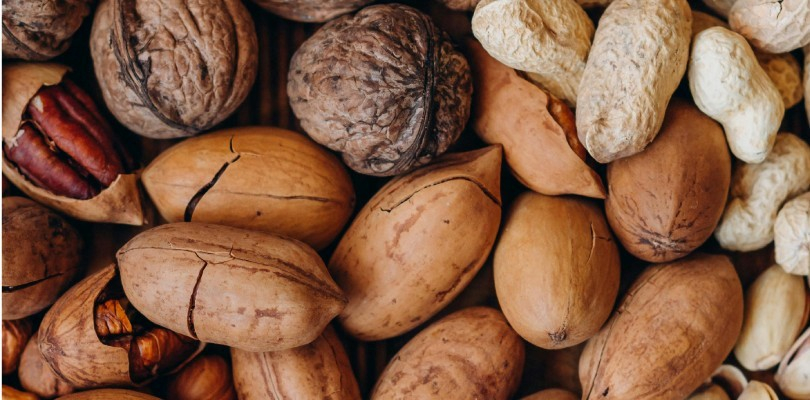 Close-up van diverse ongepelde noten, waaronder walnoten, pecannoten en pinda’s
