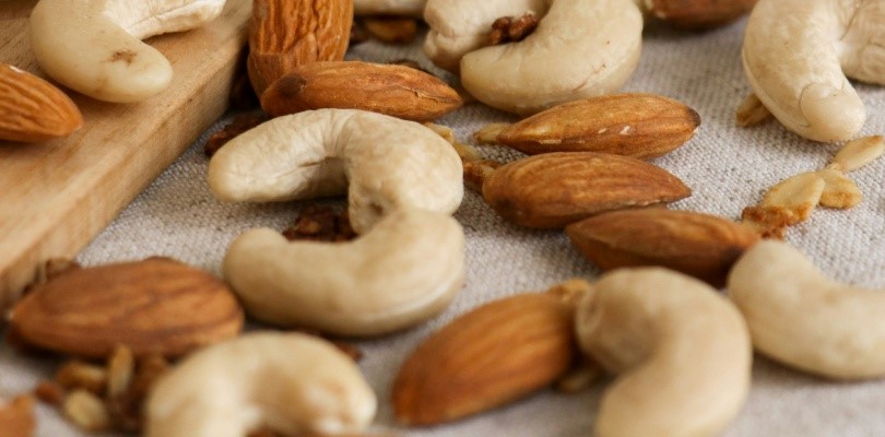 Close-up van verschillende soorten noten, waaronder amandelen en cashewnoten, verspreid op een tafel